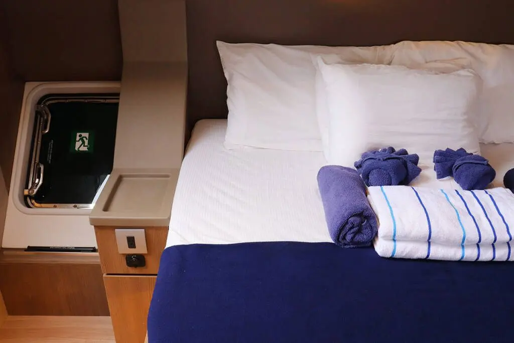 Cabin bed with white sheets and blue towels