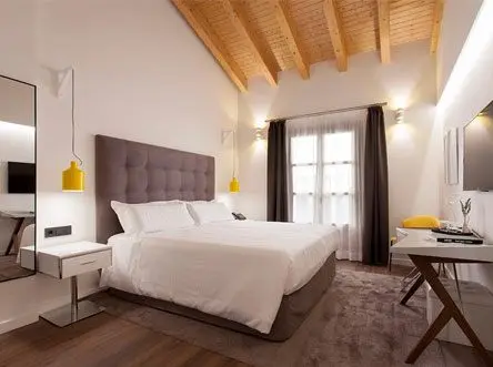 Hotel room with the double bed made up and a wooden ceiling