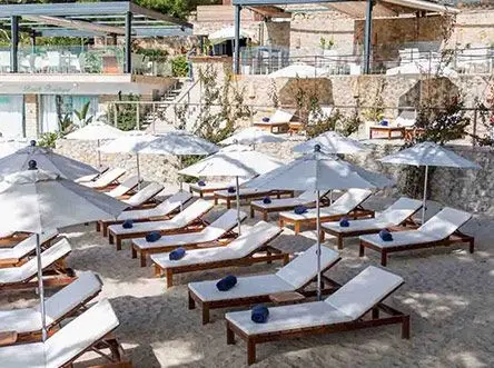 Sun loungers with blue towels under white parasols at a beach club