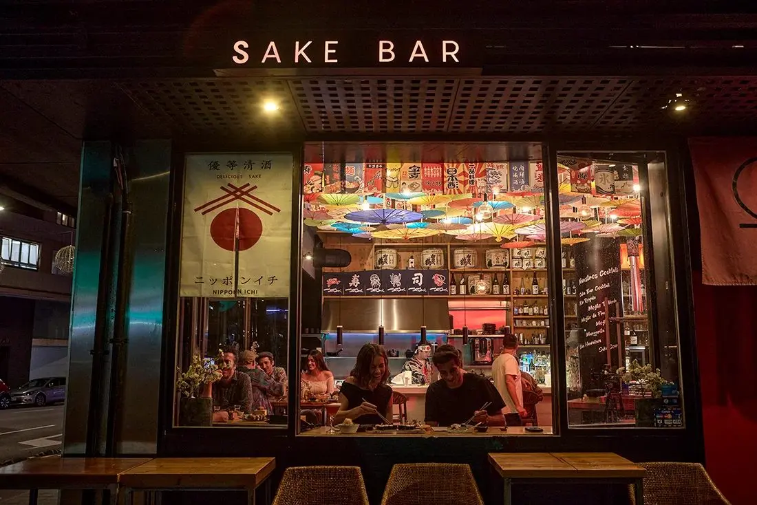 The lit-up front of Arume Sake Bar at night