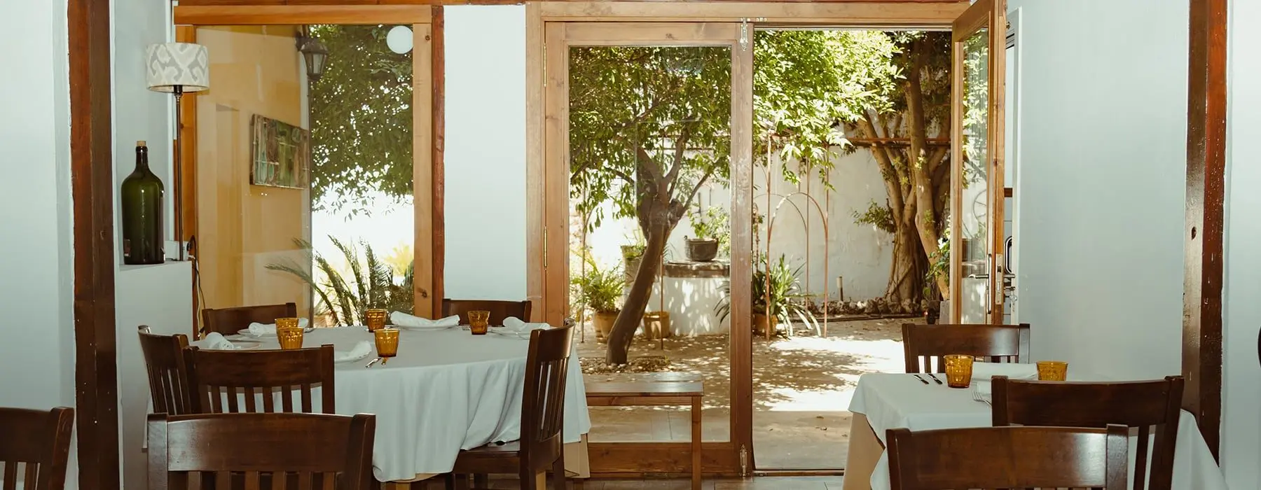 Dining room with white tablecloths opening onto a courtyard
